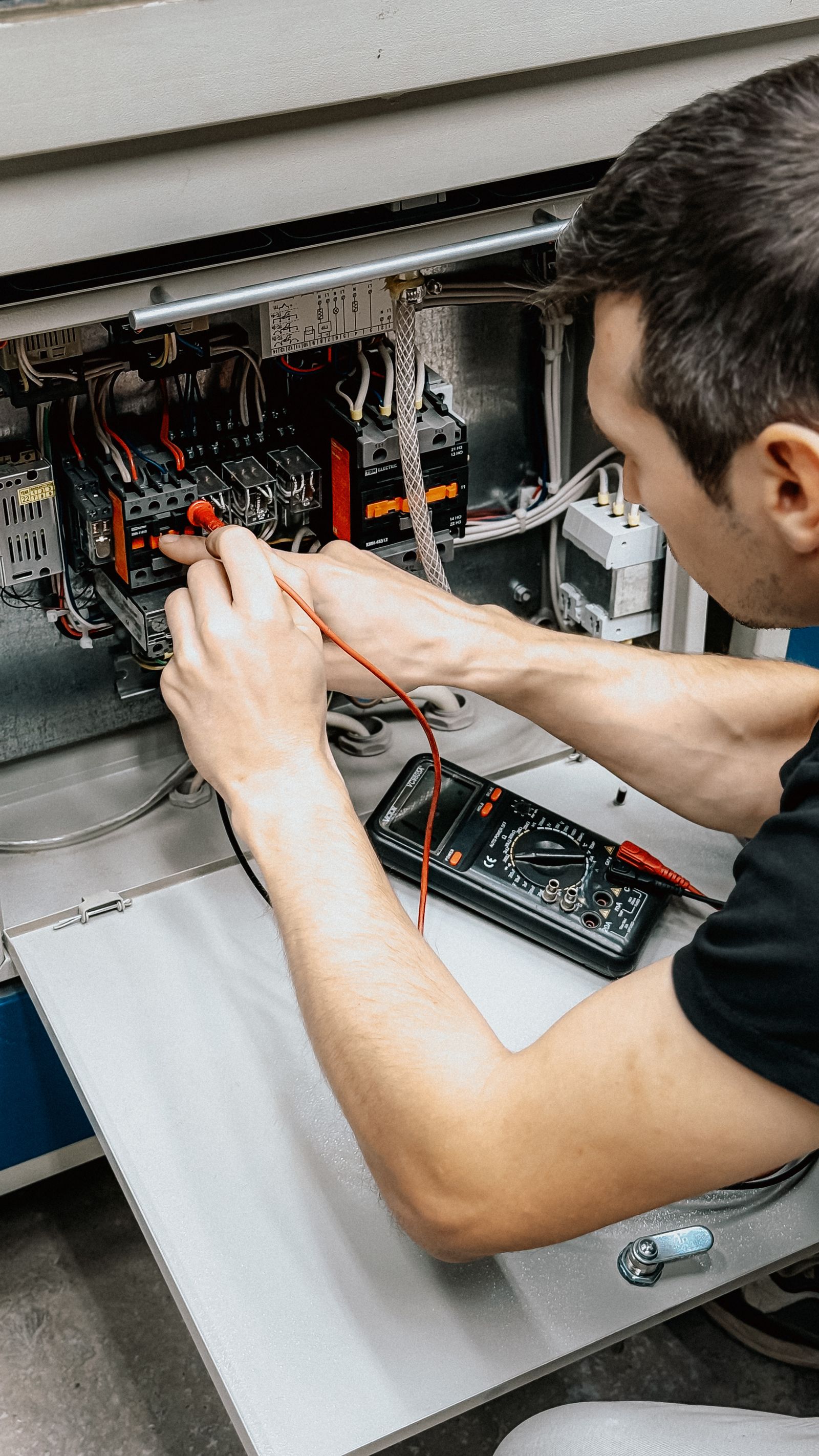 Électricien contrôlant un tableau électrique avec un multimètre